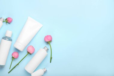 Mavi arka planda kozmetik ürünler ve güzel gül çiçekleri.