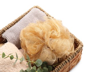 Beyaz arka planda banyo süngeri ve havluları olan sepet, yakın plan.