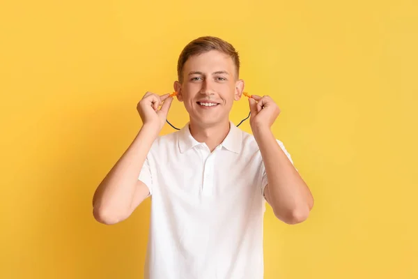 黄色の背景に耳栓を挿入ハンサムな若い男 — ストック写真