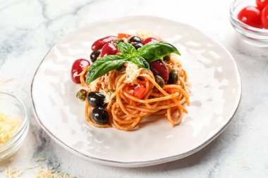 Beyaz arka planda lezzetli makarna, fesleğen ve makarna.