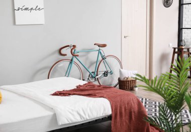 Modern yatak odasının içinde gri duvarın yanında bisiklet.