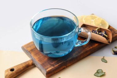 Bir fincan mavi çay ve kurutulmuş bezelye çiçeği renkli arka planda, yakın plan.