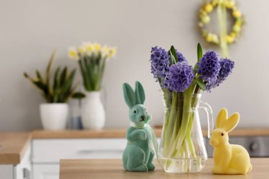 Mutfaktaki masanın üstünde taze sümbül çiçekleri ve tavşan heykelcikleri olan vazo. Paskalya kutlaması