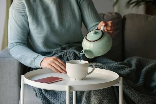 女人在饭桌上把茶壶里的蓝茶倒入杯子里 — 图库照片
