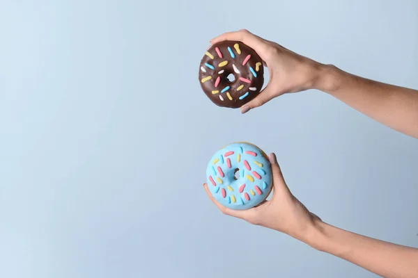 Weibliche Hände Mit Leckeren Donuts Auf Farbigem Hintergrund — Stockfoto