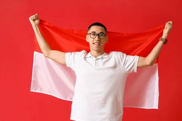 戴眼镜的年轻亚洲男子 红底上悬挂印度尼西亚国旗 — 图库照片