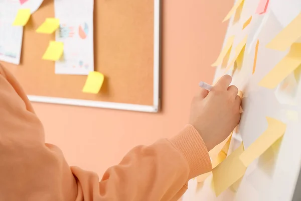 Woman Writing Sticky Note Attached Flipchart Beige Wall Closeup — Stock Photo, Image