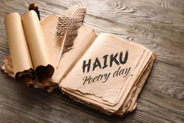 Yazılı eski kitabı aç HAIKU Şairane Gün ve ahşap arkaplanda parşömenleri olan tüy