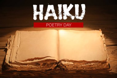 Tahta zemin üzerinde HAIKU Şairane Günü yazılı eski kitabı aç