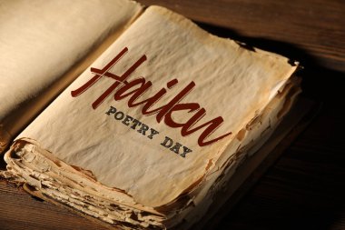 Tahta zemin üzerinde HAIKU Şairane Günü yazılı eski kitabı aç