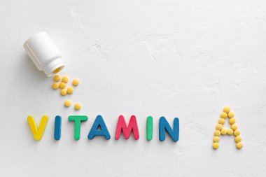 Beyaz arka planda A vitamini hapları olan şişe