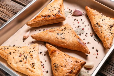 Ahşap zemin üzerinde lezzetli Özbek samsa ile fırın tepsisi