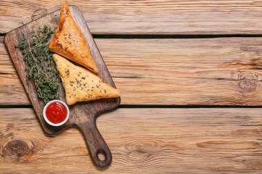 Ahşap zemin üzerinde lezzetli Özbek samsa ve domates soslu tahta.