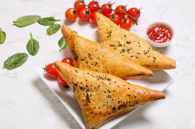Beyaz arka planda lezzetli Özbek samsa ve domates soslu tabak.