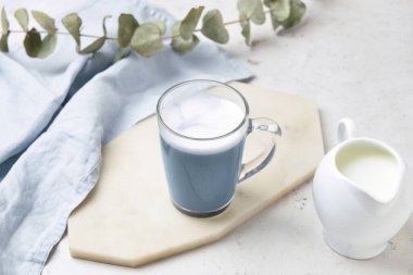 Bir bardak lezzetli Charcoal Latte ve sütle aydınlatma masasında