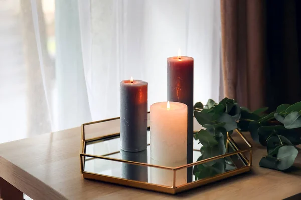 窗户附近桌上放着燃烧的蜡烛和桉树枝条的托盘 — 图库照片