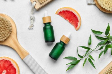 Hafif arka planda banyo malzemeleri olan greyfurt yağı şişeleri.