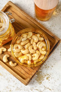 Bir kase tatlı kaju fıstığı ve bal arkaplanda.