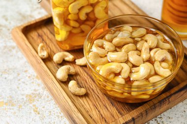 Bir kase tatlı kaju fıstığı ve bal arkaplanda.