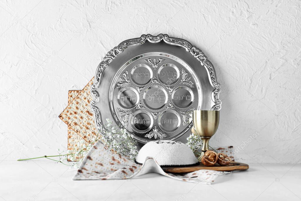 Passover Seder plate with cup of wine, kippah and matza on white background