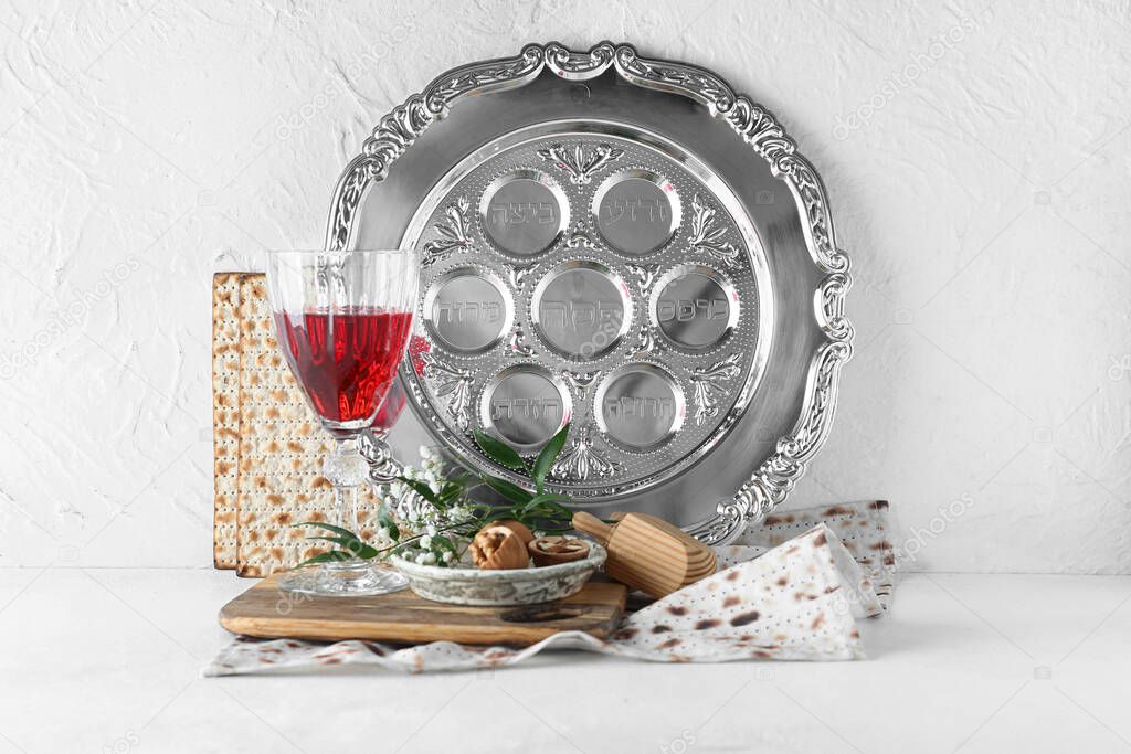 Passover Seder plate with glass of wine, walnuts and matza on white background