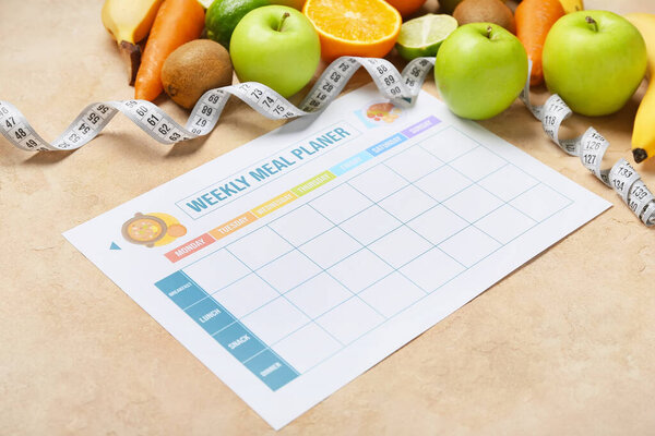 Планировщик еженедельных обедов и различные здоровые продукты на бежевом фоне