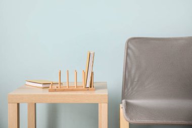 Masada kitapları ve mavi duvarın yanında sandalyesi olan ahşap düzenleyici.