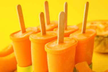 Sarı arka planda lezzetli kavunlu dondurma kutuları.