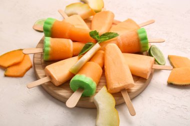 Lezzetli buzlu şeker ve hafif arka planda kavun parçaları olan bir tahta.