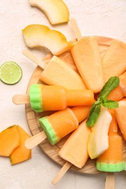 Lezzetli buzlu şeker ve hafif arka planda kavun parçaları olan bir tahta.