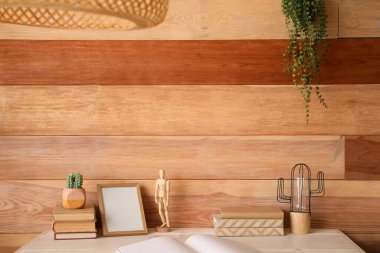 Ahşap duvarın yanında kitapları, çerçevesi ve dekorasyonu olan modern işyeri