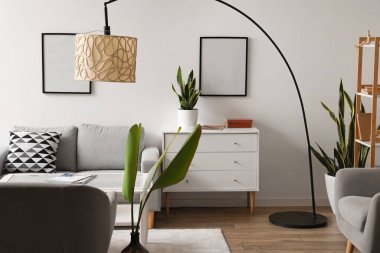 Gri kanepe, klozet ve standart lambayla aydınlık oturma odasının içinde.