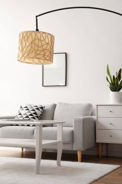 Standart lamba, kanepe ve masa olan bir oturma odası.