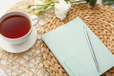 Not defteriyle güzel bir kompozisyon, bir fincan çay ve beyaz arka planda bir coşku.