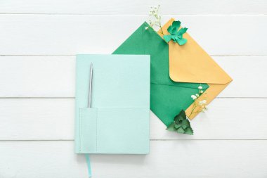 Zarflı şık defter ve beyaz ahşap arka planda çingene çiçekleri.