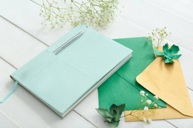 Zarflı şık defter ve beyaz ahşap arka planda çingene çiçekleri.