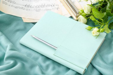 Renkli arkaplan üzerinde notlar ve güller olan şık bir defter, yakın plan