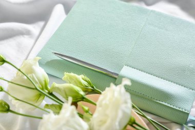 Beyaz kumaş arka planında kalem ve östoma içeren şık bir defter, yakın plan