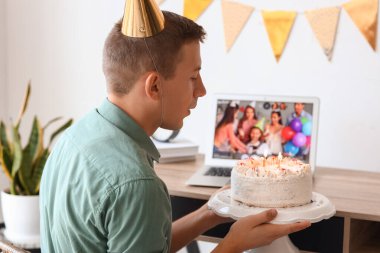 Genç adam Coronavirüs salgını nedeniyle evde online doğum gününü kutluyor.