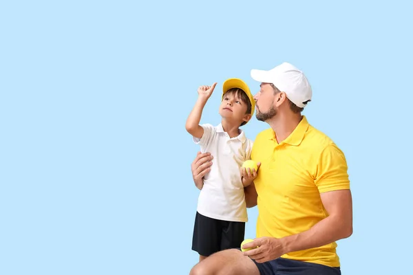 小男孩和他的教练带着蓝色背景的网球 — 图库照片