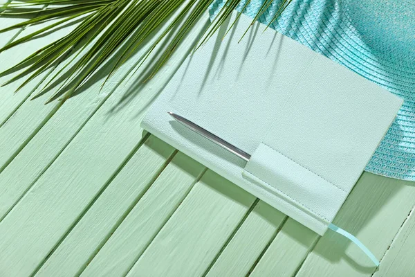 Stylový Notebook Perem Kloboukem Palmovým Listem Zeleném Dřevěném Pozadí — Stock fotografie