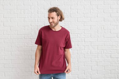 Beyaz tuğlalı tişörtlü yakışıklı genç adam.