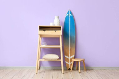 Sörf tahtası, masa ve duvar kenarındaki tabure.