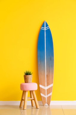 Sörf tahtası ve masa sarı duvarın yanında.