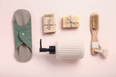 Pembe arka planda fırça, sabun ve tekrar kullanılabilir adet pedi.