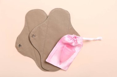Yeniden kullanılabilir adet pedleri ve pembe arka planda fincan