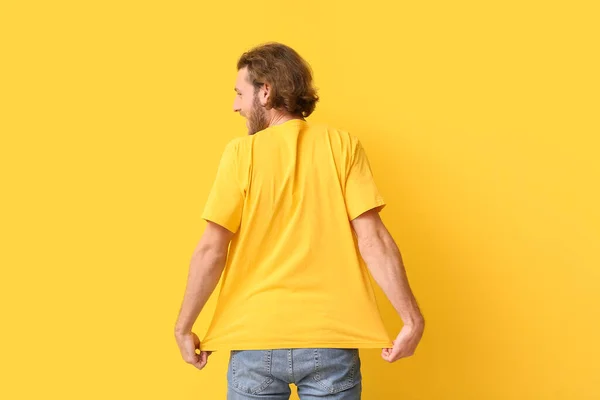 黄色の背景にスタイリッシュなTシャツでハンサムな若い男 バックビュー — ストック写真