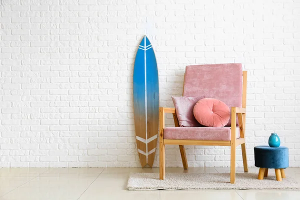 室内白砖墙附近舒适的椅子 书包和冲浪板 — 图库照片