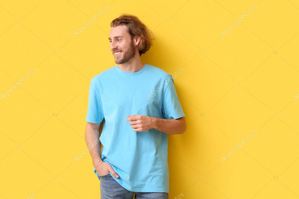 Handsome young man in stylish t-shirt on yellow background