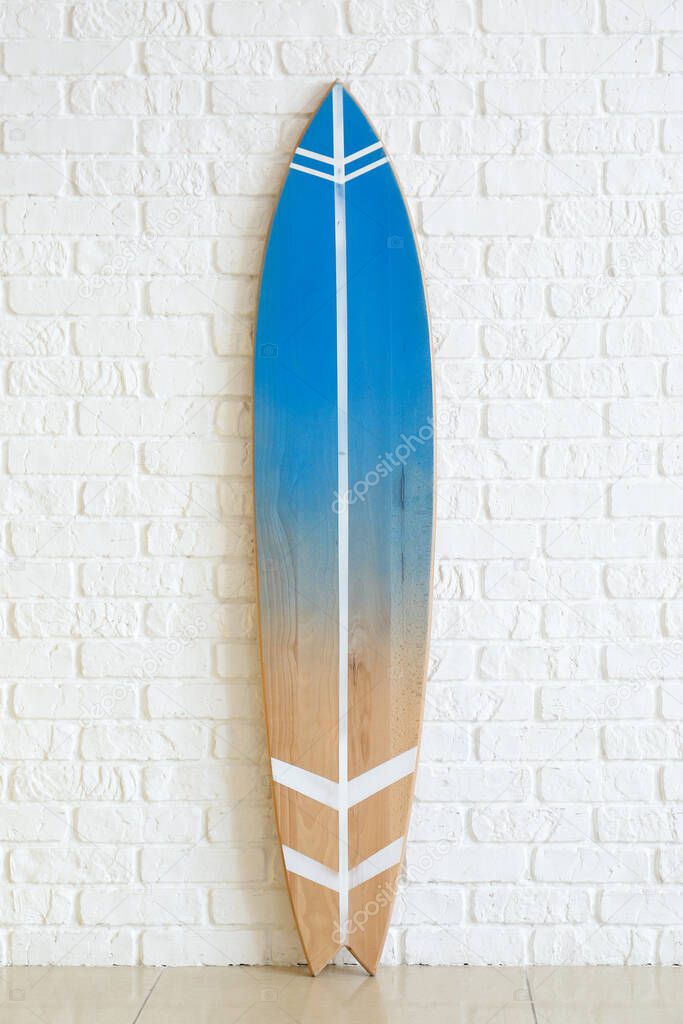 Modern surfboard near white brick wall in room